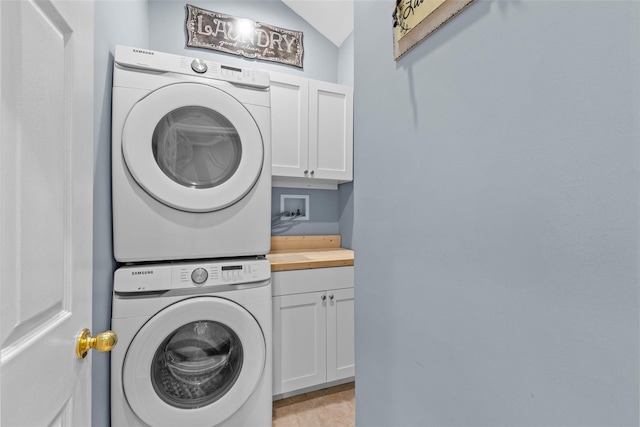 laundry room with cabinet space and stacked washer and dryer