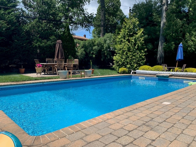 view of pool with a covered pool, outdoor dining area, and a patio area