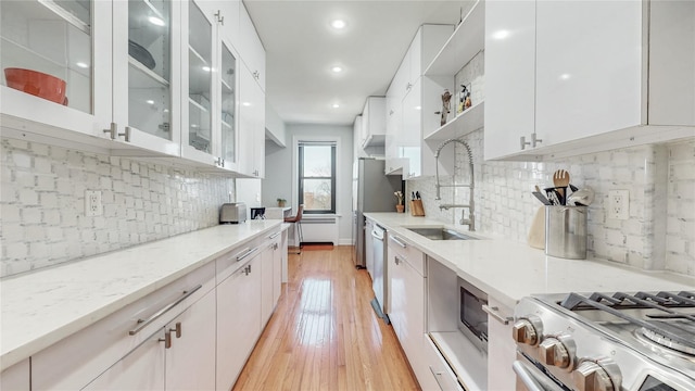 kitchen featuring open shelves, a sink, white cabinets, light wood-style floors, and appliances with stainless steel finishes