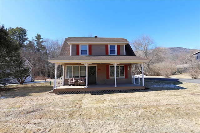 dutch colonial with covered porch, roof with shingles, and a front yard