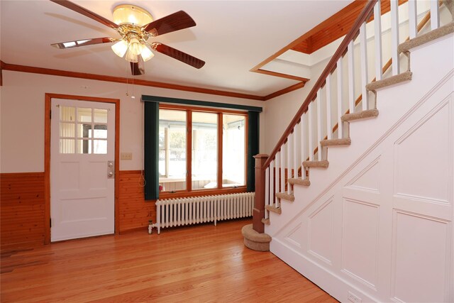 entryway featuring crown molding, radiator, stairway, wainscoting, and light wood-type flooring