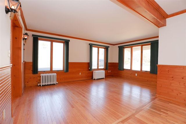 unfurnished room with radiator, light wood-style floors, crown molding, and wainscoting