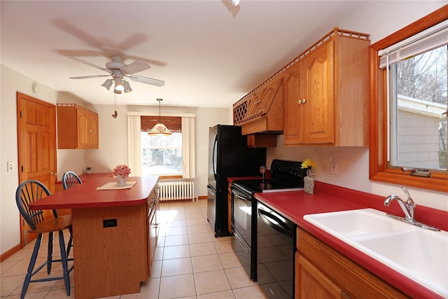 kitchen with a breakfast bar area, radiator, a kitchen island, a sink, and black appliances