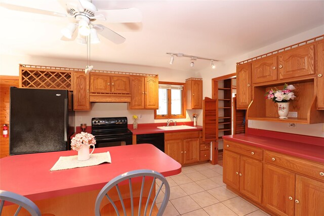 kitchen with light tile patterned floors, custom range hood, brown cabinets, black appliances, and a sink