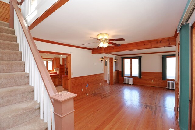 interior space featuring light wood-style floors, radiator heating unit, stairs, and wainscoting