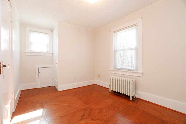 spare room featuring radiator and baseboards