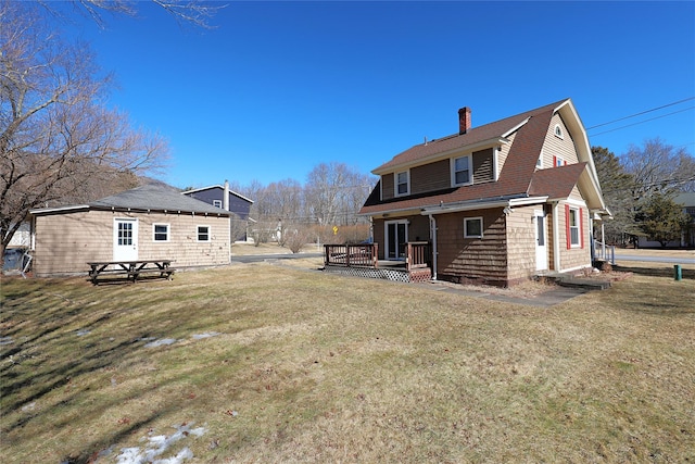 back of house with a shingled roof, a gambrel roof, a yard, a wooden deck, and a chimney