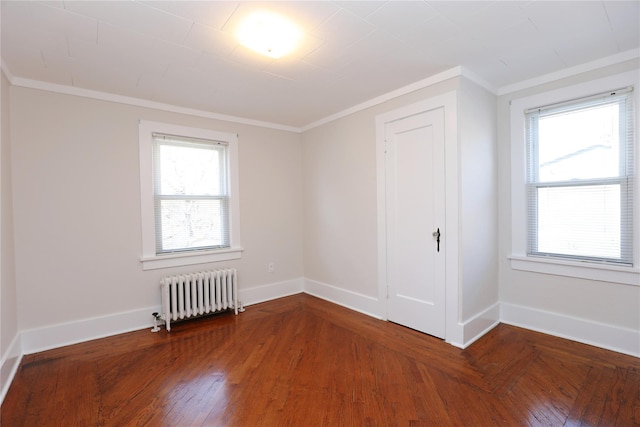 spare room with radiator, parquet flooring, baseboards, and ornamental molding