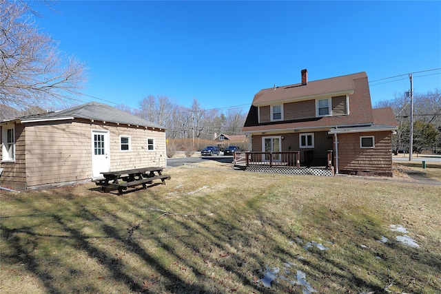 rear view of house featuring a deck, a yard, and a chimney