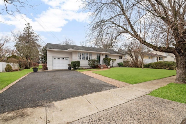 ranch-style home featuring a garage, driveway, a front yard, and fence