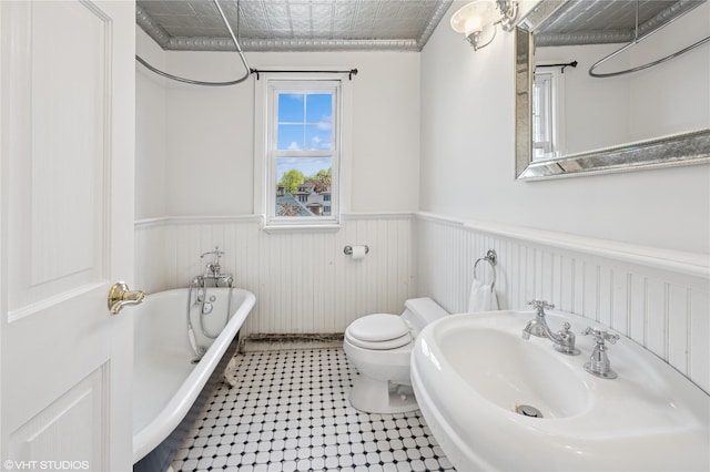 119 Cassilis Ave, Bronxville, NY 10708 - bathroom featuring a wainscoted wall, a freestanding bath, toilet, a sink, and an ornate ceiling