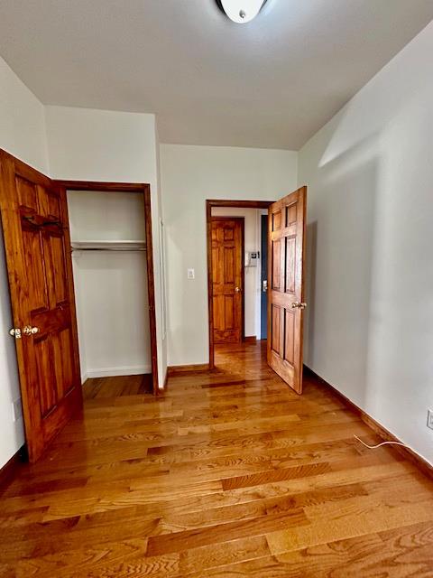 unfurnished bedroom featuring light wood-type flooring, a closet, and baseboards