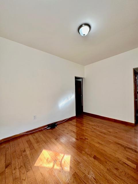 unfurnished room with hardwood / wood-style floors and baseboards