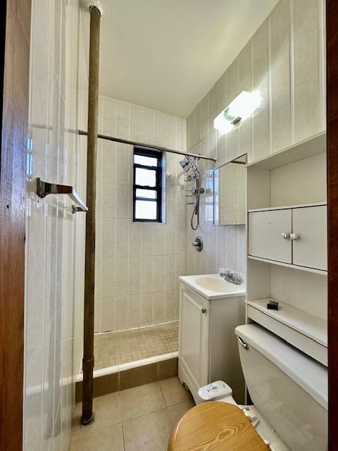 full bathroom with toilet, vanity, tiled shower, and tile patterned floors