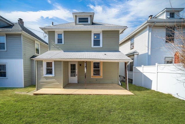 rear view of property featuring a yard and fence