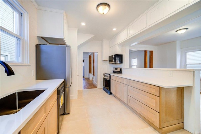 kitchen with light brown cabinets, light countertops, light tile patterned floors, appliances with stainless steel finishes, and a sink