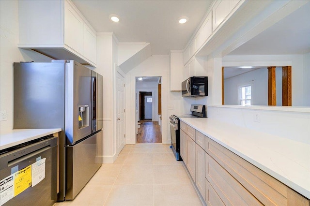 kitchen with light countertops, white cabinets, light tile patterned floors, and appliances with stainless steel finishes