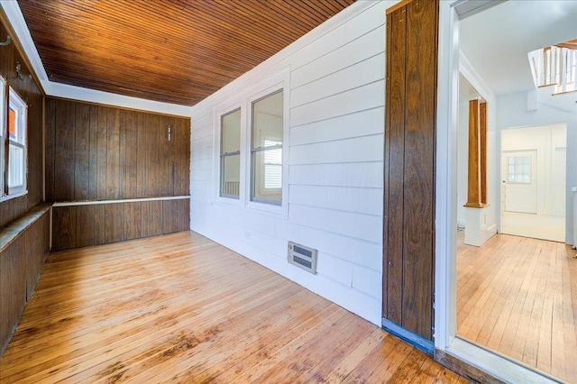 empty room featuring wooden walls, wooden ceiling, and hardwood / wood-style flooring