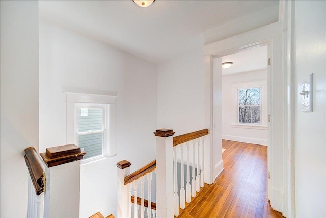 hall featuring baseboards, an upstairs landing, and wood finished floors