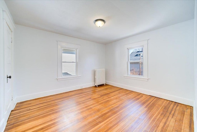 unfurnished room with light wood finished floors, radiator heating unit, and baseboards