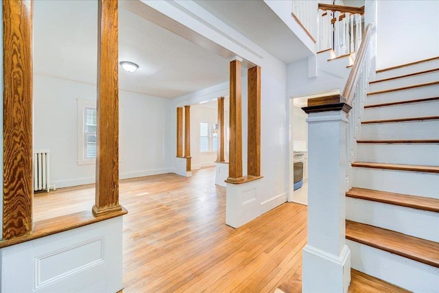 staircase with decorative columns, baseboards, wood finished floors, and radiator heating unit