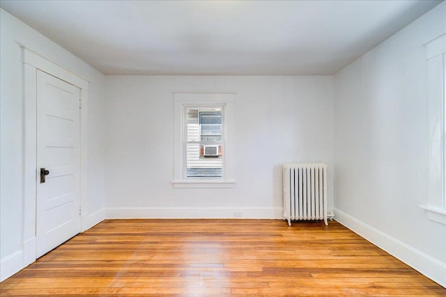 empty room with light wood-style flooring, radiator, and baseboards