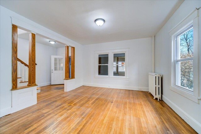 unfurnished room with a wealth of natural light, light wood-style flooring, and radiator