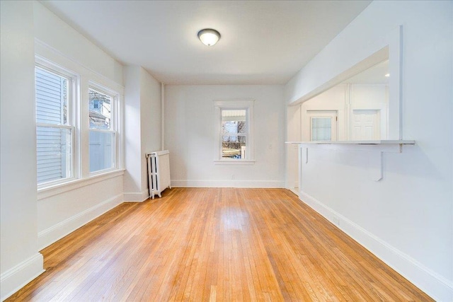 unfurnished room featuring light wood-style flooring, radiator heating unit, and baseboards