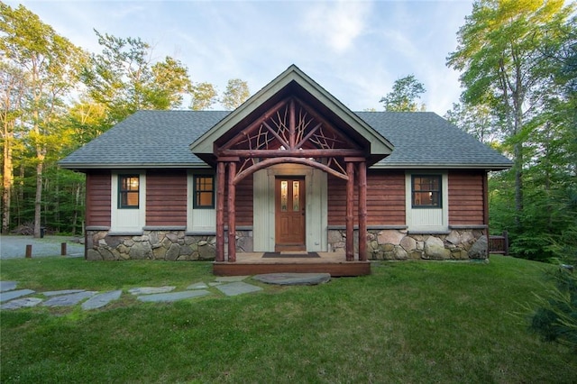 view of front of house featuring stone siding, roof with shingles, and a front lawn