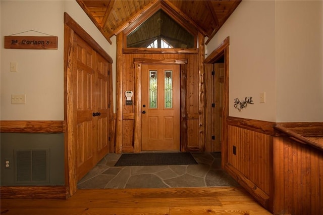 foyer with lofted ceiling, wood ceiling, visible vents, and wainscoting