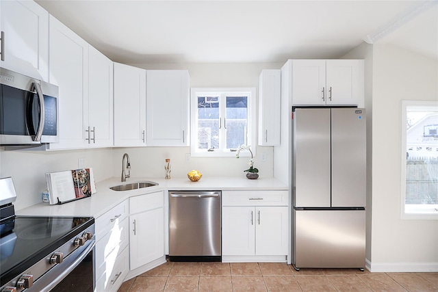 kitchen with light tile patterned floors, plenty of natural light, stainless steel appliances, and a sink