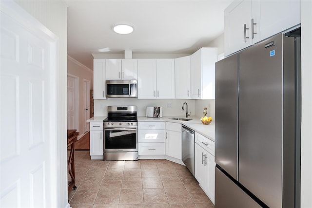 kitchen featuring light tile patterned flooring, a sink, white cabinets, light countertops, and appliances with stainless steel finishes