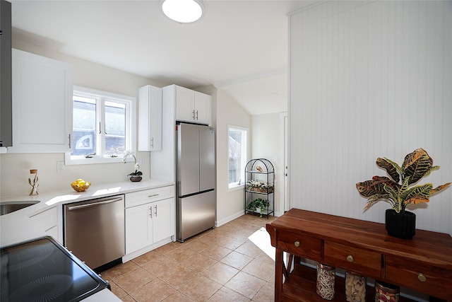 kitchen featuring white cabinets, vaulted ceiling, stainless steel appliances, light countertops, and light tile patterned flooring