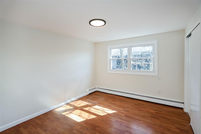 unfurnished room with baseboards, baseboard heating, and wood finished floors