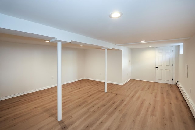 finished basement featuring baseboards, baseboard heating, light wood-type flooring, and recessed lighting