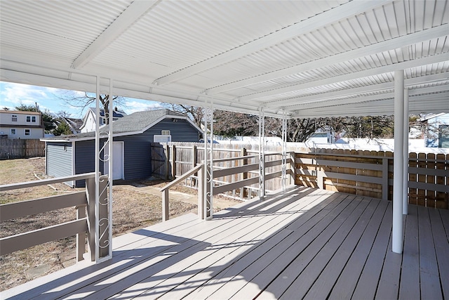 wooden deck with a fenced backyard, an outdoor structure, and a shed