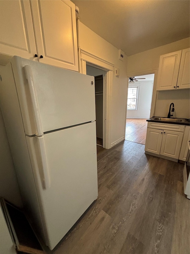 kitchen with white cabinetry, dark wood-style floors, freestanding refrigerator, and a sink