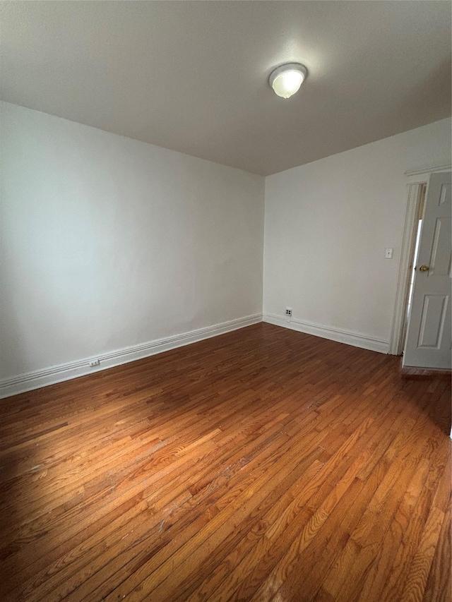 spare room featuring baseboards and dark wood-style flooring