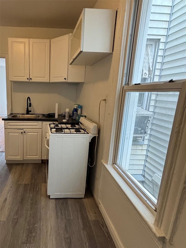 kitchen featuring white gas range, dark wood-style flooring, white cabinetry, and a sink