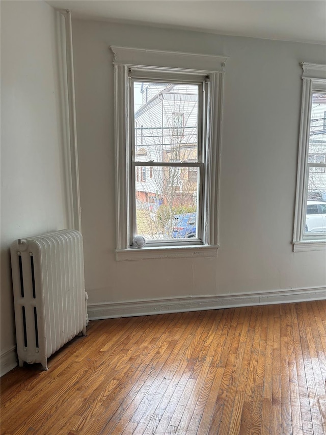 unfurnished room with hardwood / wood-style floors, radiator, and baseboards