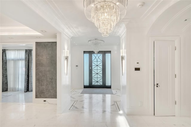 entryway with crown molding, arched walkways, marble finish floor, and a chandelier