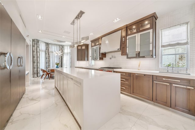 kitchen with marble finish floor, a center island, light countertops, glass insert cabinets, and extractor fan