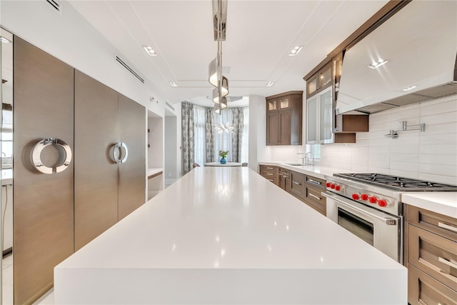 kitchen featuring backsplash, a kitchen island, premium range hood, light countertops, and stainless steel range