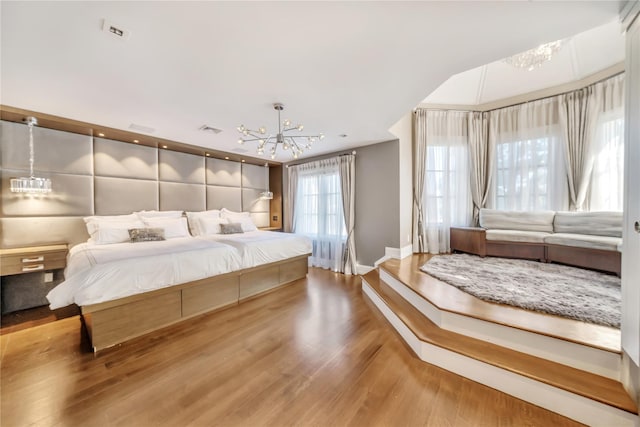 bedroom featuring a notable chandelier, baseboards, visible vents, and wood finished floors