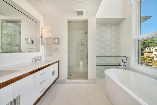 full bathroom with visible vents, double vanity, a freestanding tub, a sink, and a shower stall