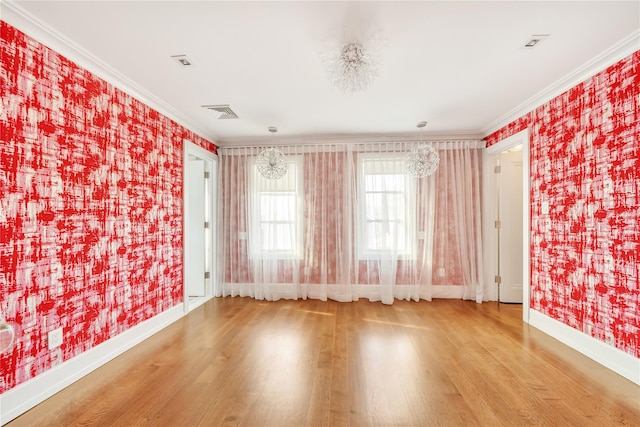 spare room featuring wallpapered walls, crown molding, wood finished floors, and baseboards