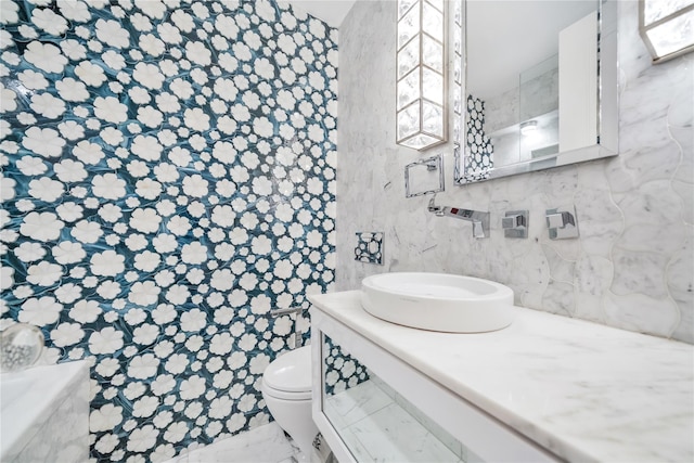 full bath featuring a bathing tub, marble finish floor, toilet, and a sink