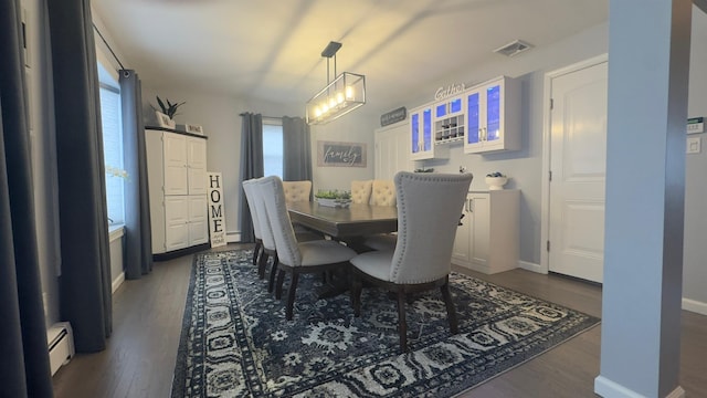 dining space featuring baseboards, dark wood-style floors, visible vents, and a baseboard radiator