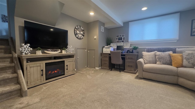 living area featuring recessed lighting, light colored carpet, a glass covered fireplace, and stairs