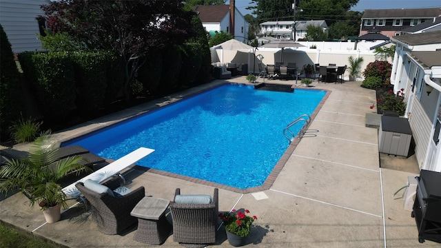 view of swimming pool with outdoor dining space, a fenced in pool, a fenced backyard, a diving board, and a patio area